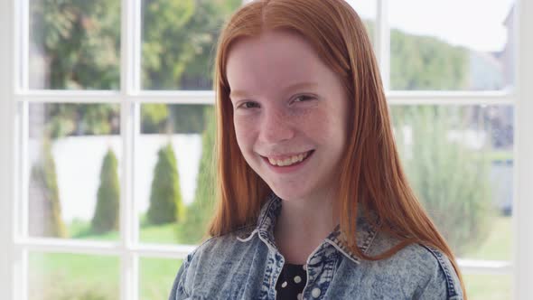 Red Haired Girl with Freckles Smiling Against White Window