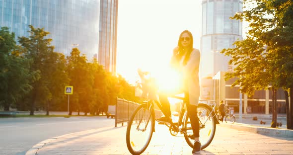 Girl with classic bicycle at sunset in city street, has a bike walk in evening. Asian young woman