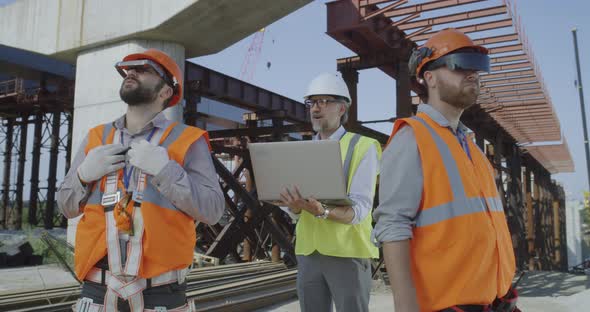 Male Engineers Making Plan of Construction Site alt