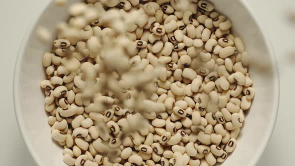 White Beans Falling Into A White Bowl
