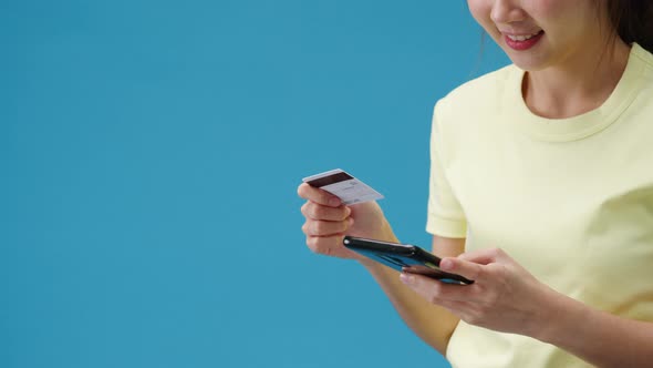 Young Asia lady using phone and credit bank card with positive expression.