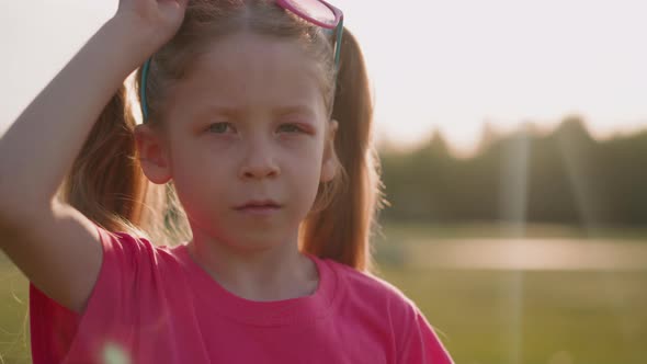 Little Girl with Swollen Eyelid Takes Off Glasses at Sunset alt