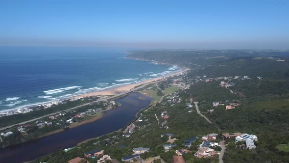 Drone shot of Wilderness hills in South Africa - drone is facing Wilderness beach, the bay and the o alt