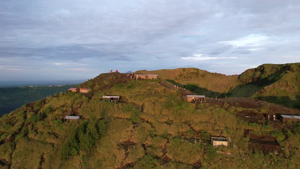 aerial circling local huts on a volcano rim during sunrise in Bali Indonesia alt