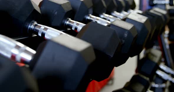 Dumbbells on a rack in fitness studio 4k alt