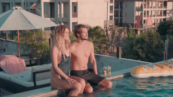 Cheerful Couple Sitting at Edge of Pool alt