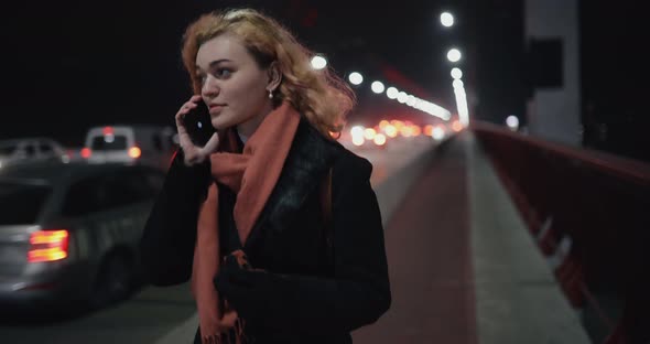 Girl with Smartphone Walks Along the Highway
