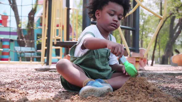 African American boy play sand in sand yard in playground