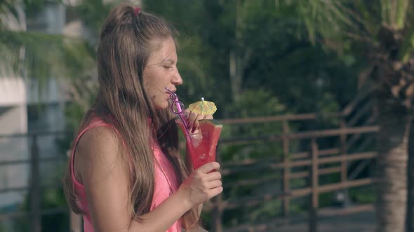Summer Wind Blows Through Long Hair and Girl Tastes Cocktail alt