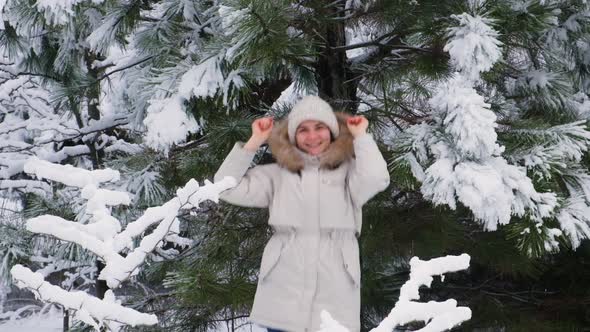 A Woman Jumps and Has Fun in the Winter Snowy Forest Snowflakes Fly By Slow Motion alt
