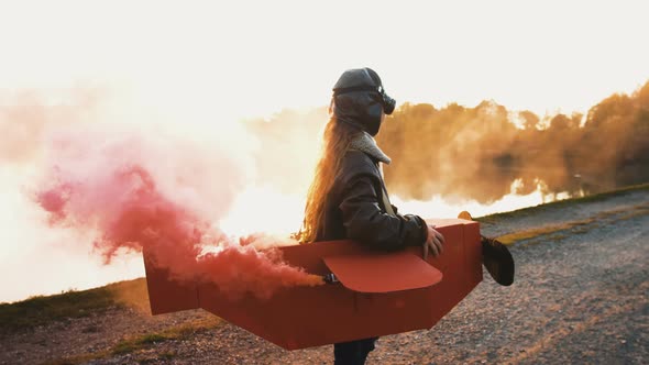 Aviator Boy Running Along Sunset Lake in a Cardboard Plane alt