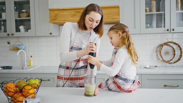 Young Mother Preparing Healthy Smoothie with Little Daughter at Kitchen Slow Motion alt