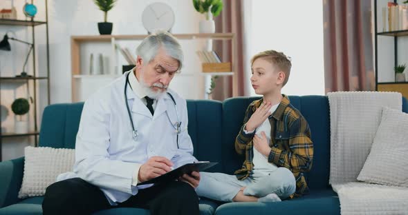Doctor Talking with Teen Boy Patient, Filling Medical Card During Home Medical Appointment alt