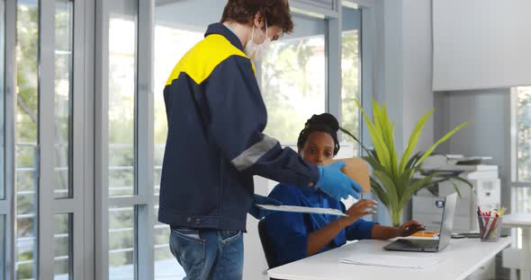African Female Consumer Signing Document to Receive Parcel From Courier in Protective Mask alt