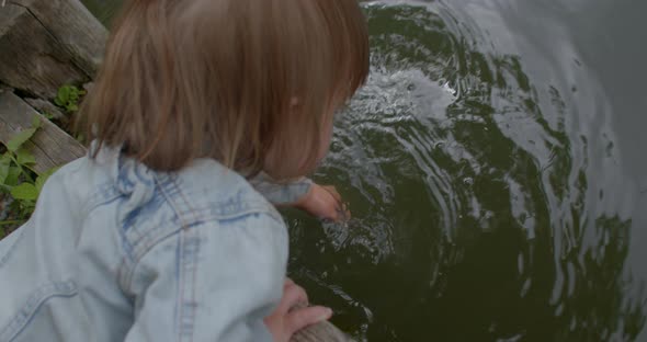Little Girl Child Touches Water Lake Hands Explores World Waves Lake Drops Water alt