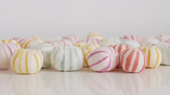 Striped assorted sugar sweet bonbons on white 4K tilting video alt