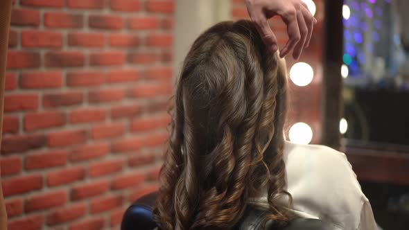 Long Brown Hair Curls with Hairdresser Spraying Fixation Spray in Slow Motion alt