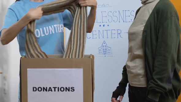 Smiling Lady Volunteer Giving Warm Clothes for Homeless Woman, Support Center alt