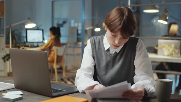 Young Businesswoman Working with Papers Late in Office alt