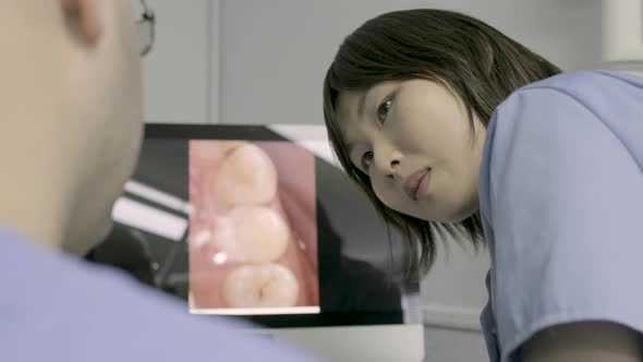 Dentist and dental assistent discussing treatment in front of computer alt