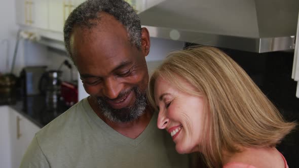 Happy romantic diverse senior couple slow dancing in kitchen alt
