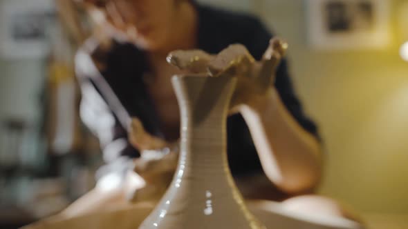 Young Female Potter Pulls the Neck of an Earthenware Vessel on Potter's Wheel