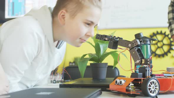 Teenage Boy Playing with Robot in Class