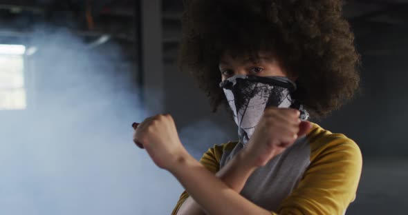 Portrait of african american woman wearing face mask gesturing stop sign in empty parking garage alt