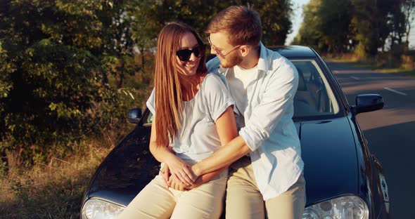 Happy Couple Sitting in Car on Sunset