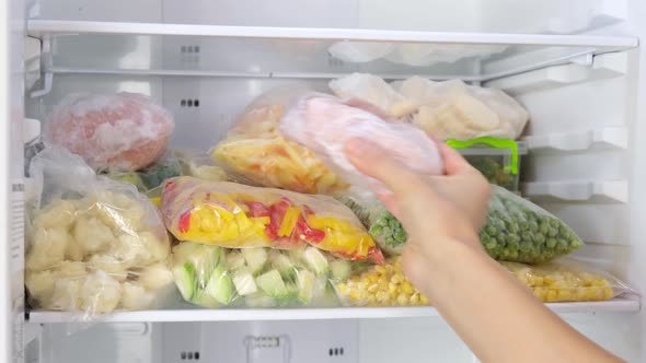 Female Hands pulls frozen meat out of the fridge