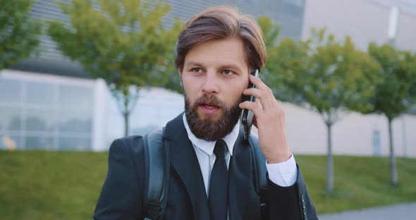 Bearded Office Manager with Backpack which Has Phone Conversation alt