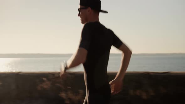 Running Man On Sea Coast Road Half Marathon. Runner Man In Sportswear Preparing To Triathlon. alt