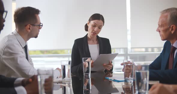 Group of Businesspeople Sitting in Meeting Room and Listening to Female Speaker alt
