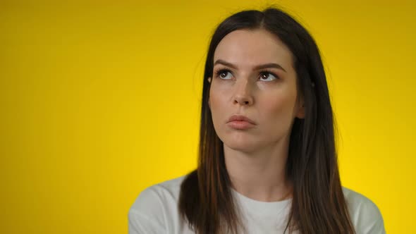 A Thoughtful and Annoyed Young Longhaired Woman Looks Up Seriously alt