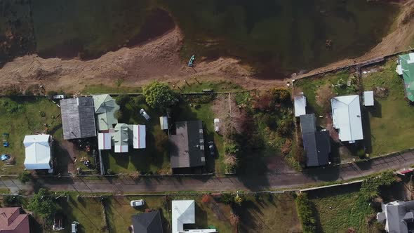 small peninsula with houses surrounded by water drone flying up