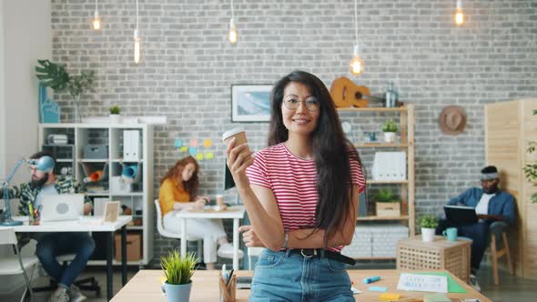 Portrait of Beautiful Asian Businesswoman Standing in Office with To Go Coffee alt
