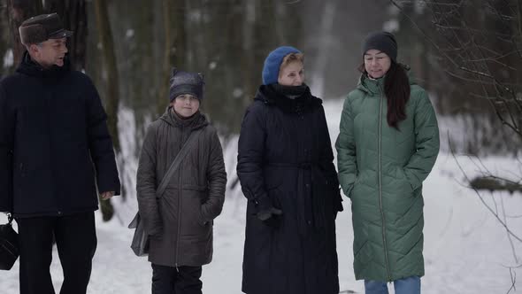 Family Is Walking at Winter Little Girl with Mother and Grandparents Is Strolling in Snowy Park or alt