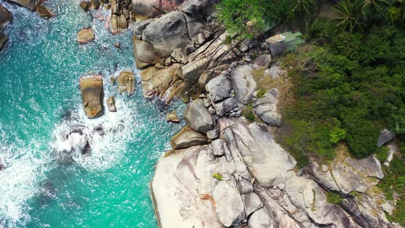 Beautiful cliffs naturally caved by ocean waves splashing and foaming on rocky coastline of tropical alt