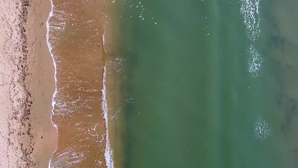Vertical orientation video: Small sea waves. Soft waves on a sandy beach. Seascape background