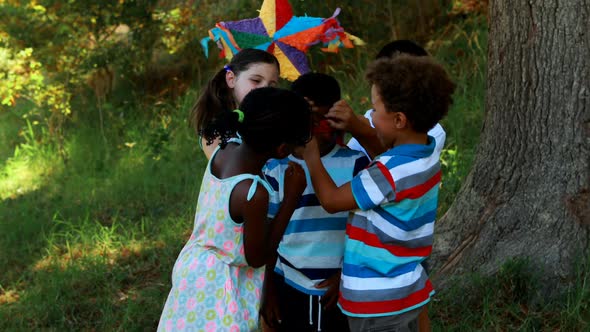 Group of kids tying blindfold on their friends eyes in park alt