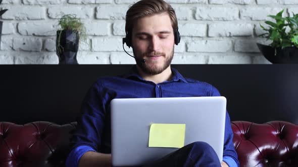Confident man wearing headset speaking and watching business webinar training, listening to lecture. alt