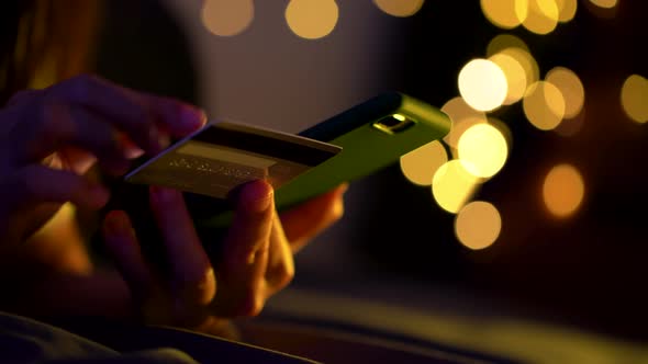 Close up shot of female hand holding credit card using smart phone for shopping online