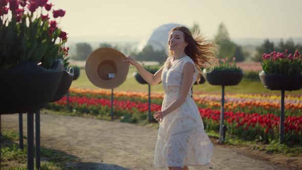 Pretty Girl Jumping with Lightness and Elegance in Spring Flower Garden Outside alt
