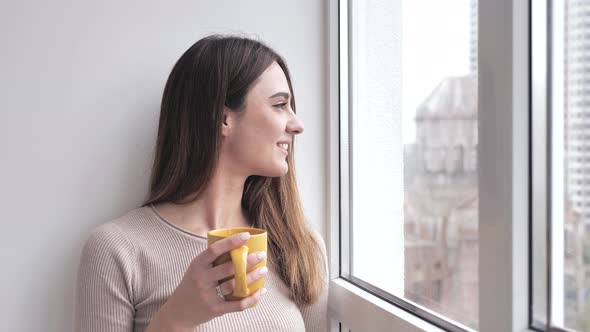 Relaxed Attractive Young Woman Having a Rest and Drinking a Cup of Tea or Coffee in Front of the alt