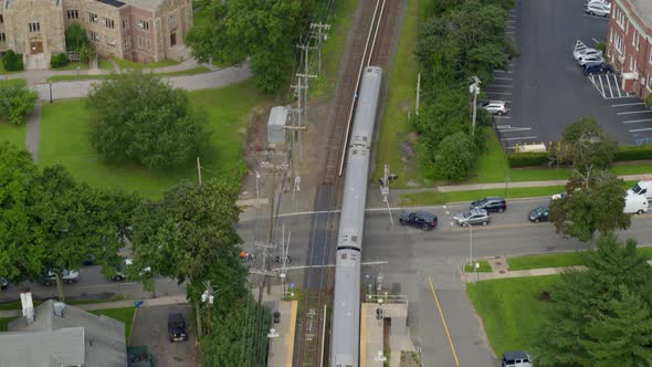 Following Aerial Shot of Train Passing Through Garden City Long Island alt