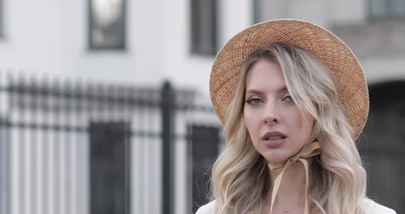 Cheerful Woman with Beautiful Big Blue Eyes Long Fair Hair White Hat in King White Dress Poses for