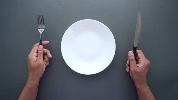 Men Holding Cutlery with Empty Plate on Black Background alt