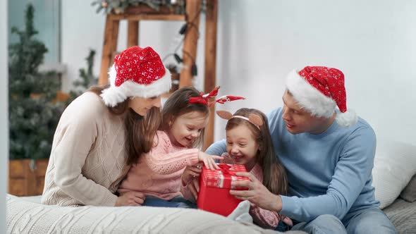Amazed Female Child Getting Christmas Present From Mother and Father Enjoy Childhood alt