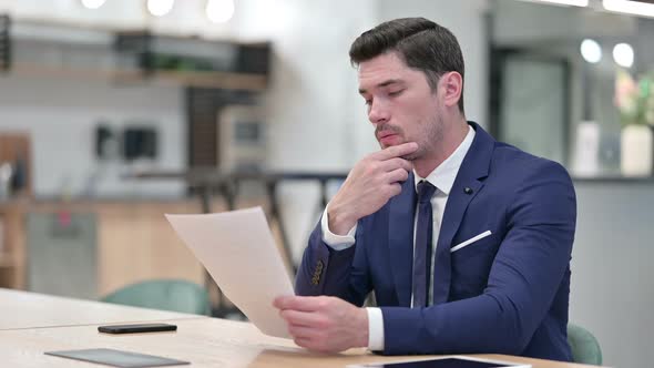 Focused Businessman Doing Paperwork in Office  alt