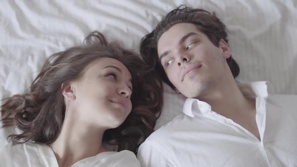 Cute Man and Woman Falling on the Bed and Looking at Each Other with Love alt